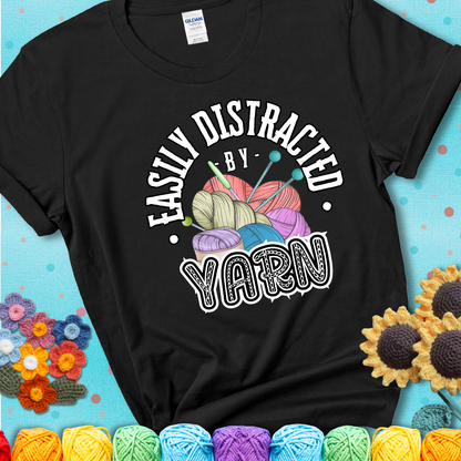 If yarn steals your focus every Design reads 'Easily Distracted By Yarn', perfect crochet gift for yarn lovers; showing a black tee with a teal sunflower background
