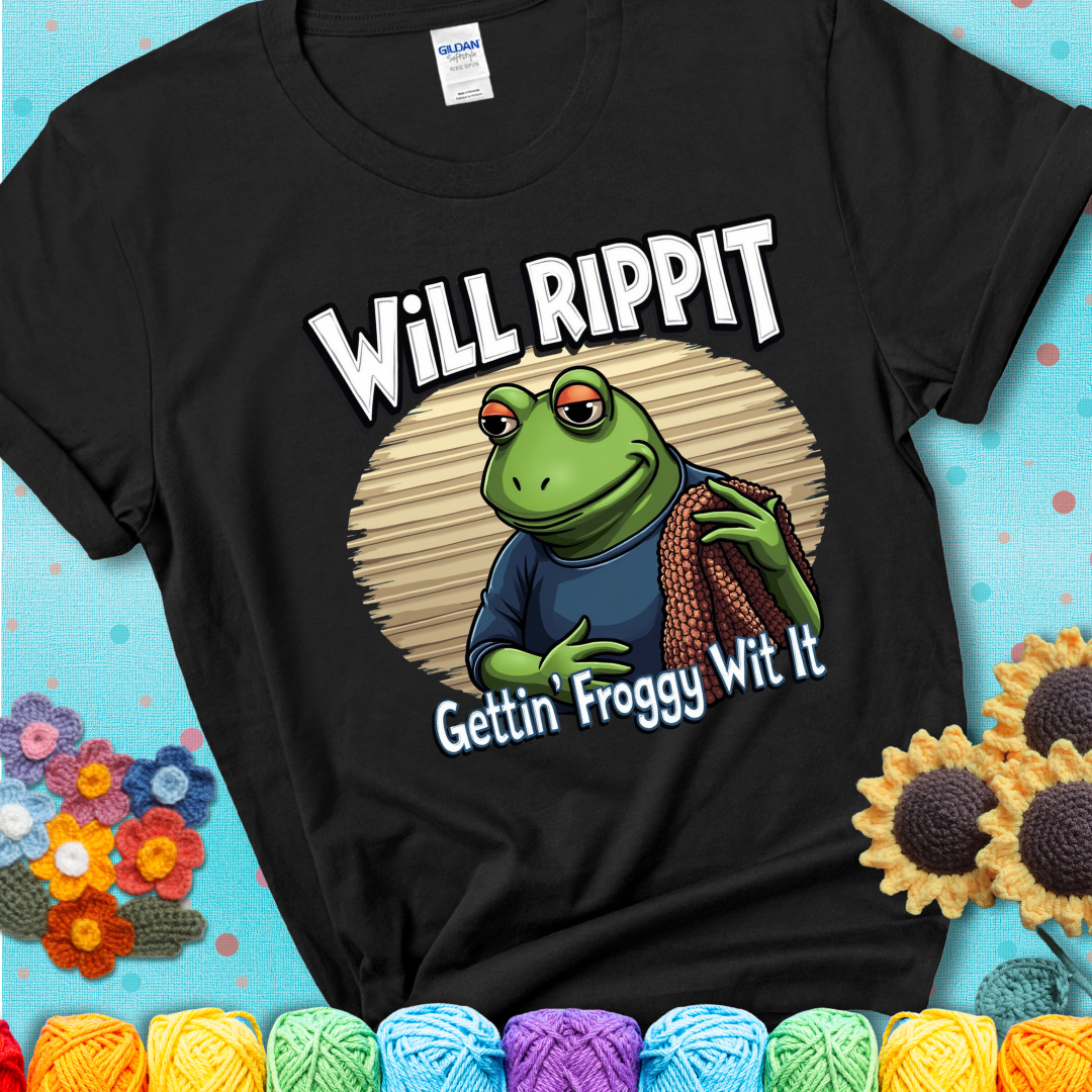 Cool frog holding a yarn blanket. Text reads: “Will Rippit Gettin’ Froggy Wit It.” A hip and humorous crochet black tee for yarn lovers with rhythm.