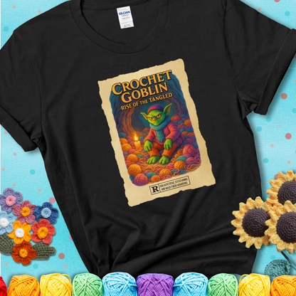 Crochet goblin surrounded by chaotic yarn stash in a cave-like lair. Text reads: “Crochet Goblin: Rise of the Tangled.” A funny fantasy-style black tee for yarn hoarders and goblin-mode crafters.