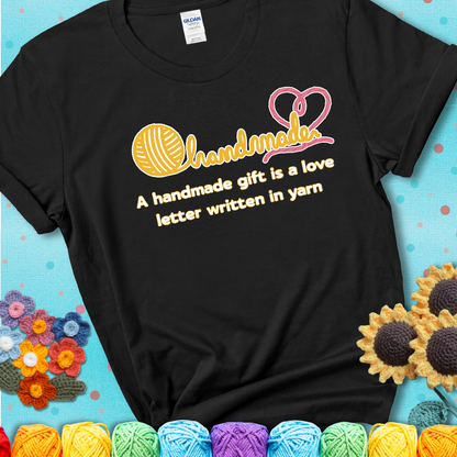 Soft script-style design with heart detail. Text reads: “A Handmade Gift Is a Love Letter Written in Yarn.” A sweet and sentimental shirt for crocheters who craft from the heart, showing a black tee with a teal sunflower background
