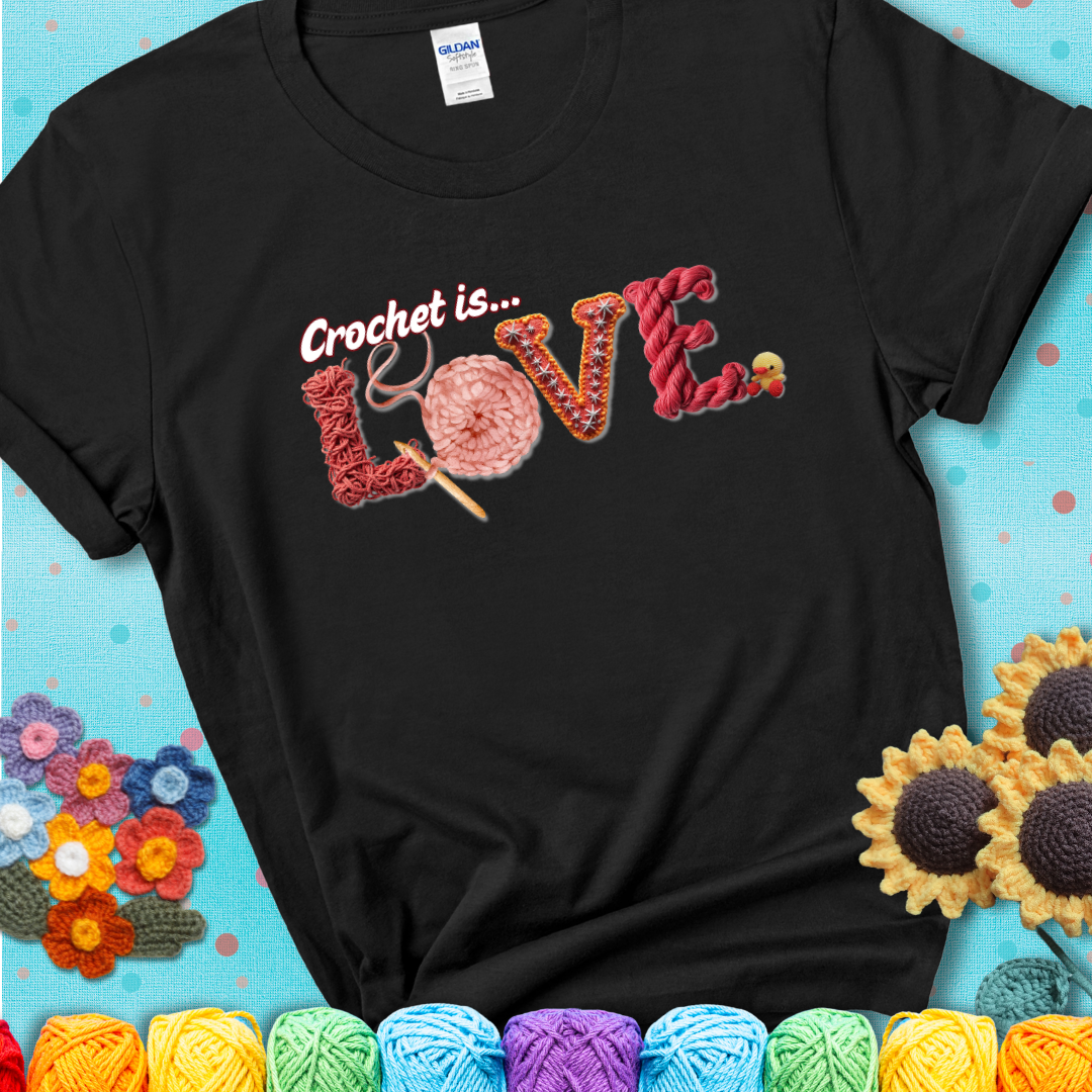 A black t-shirt featuring the word "LOVE" spelled with different crochet textures and yarn in red tones, with the phrase “Crochet is…” above in script.