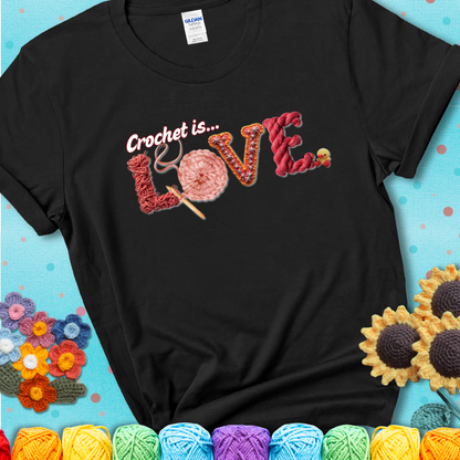A black t-shirt featuring the word "LOVE" spelled with different crochet textures and yarn in red tones, with the phrase “Crochet is…” above in script.