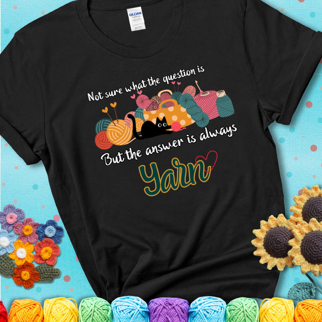 Black t-shirt with a black cat beside a basket of colorful yarn and the phrase, “Not Sure What The Question Was, But The Answer Is Yarn.”