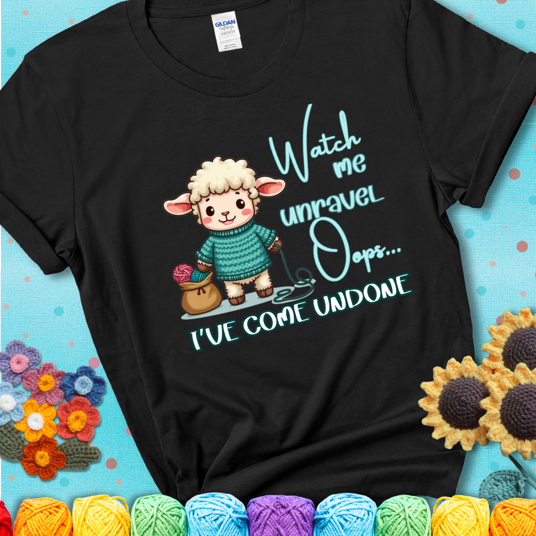 Black t-shirt with a cute sheep holding yarn looks startled with the phrase “Watch me unravel… Oops, I’ve come undone.” Perfect mix of whimsy and yarn life chaos.