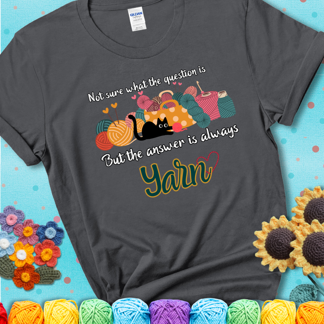 Charcoal t-shirt with a black cat beside a basket of colorful yarn and the phrase, “Not Sure What The Question Was, But The Answer Is Yarn.”