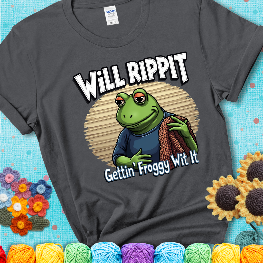 Cool frog holding a yarn blanket. Text reads: “Will Rippit Gettin’ Froggy Wit It.” A hip and humorous crochet charcoal grey tee for yarn lovers with rhythm.