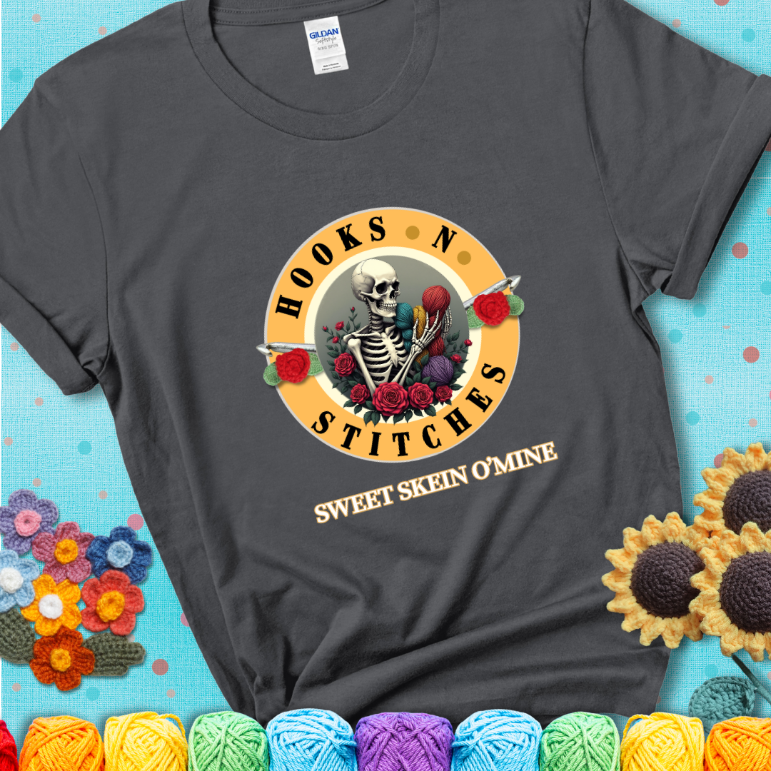 Charcoal t-shirt with a skeleton holding colorful yarn, roses, crochet hooks, and the phrases “Hooks ’N Stitches” and “Sweet Skein O’Mine.”