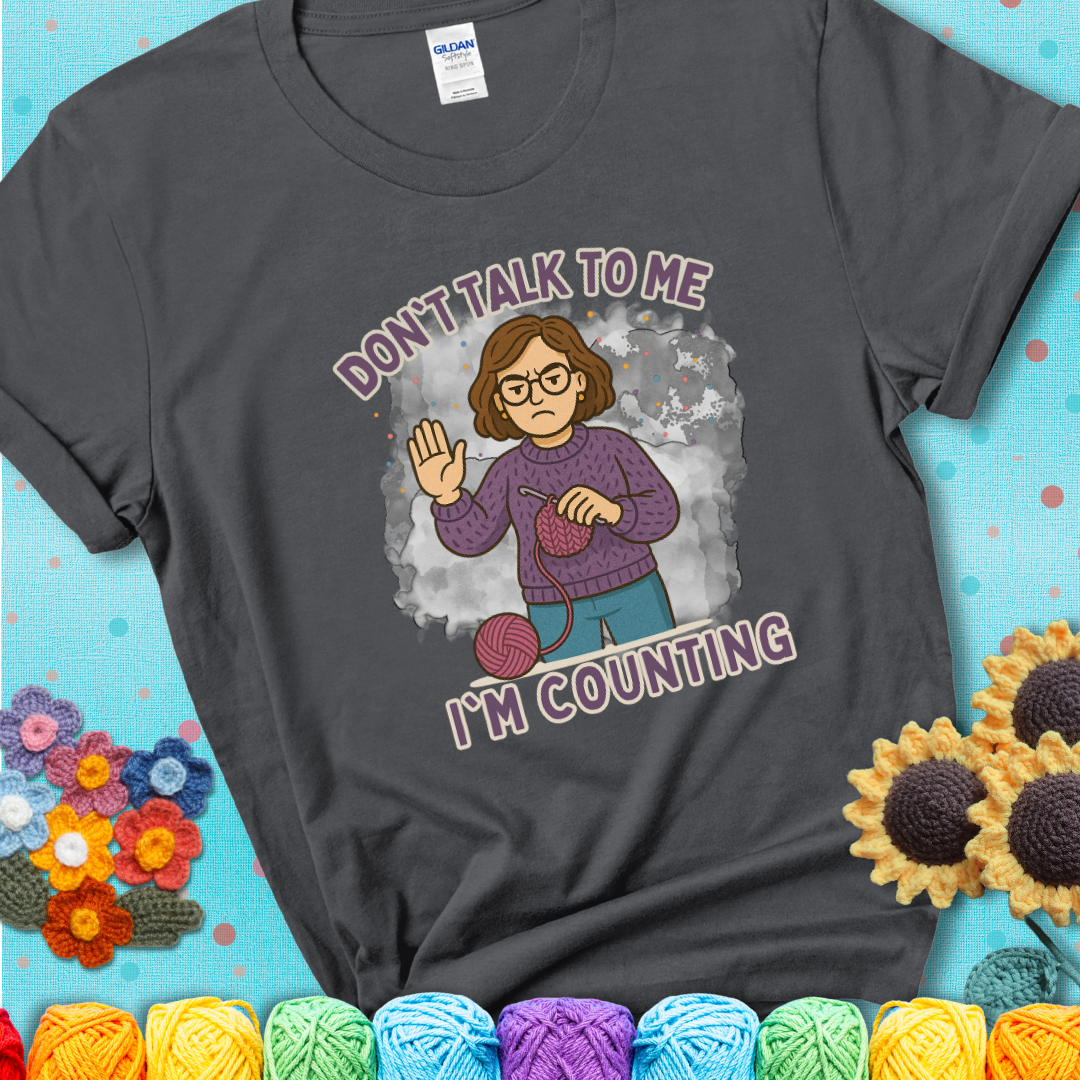 Charcoal t-shirt with an annoyed maker holding up a hand beside yarn, with the phrase “Don’t Talk To Me, I’m Counting.”