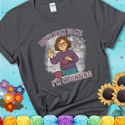 Charcoal t-shirt with an annoyed maker holding up a hand beside yarn, with the phrase “Don’t Talk To Me, I’m Counting.”