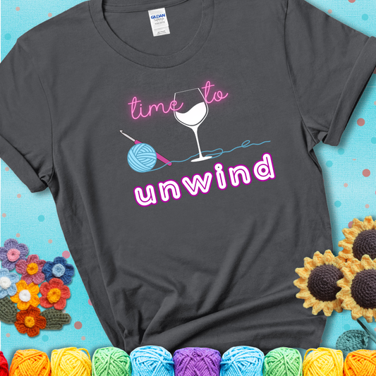 Wine down with your yarn out Design reads 'Time To Unwind' , perfect crochet gift for yarn lovers showing a charcoal grey tee with a teal sunflower background