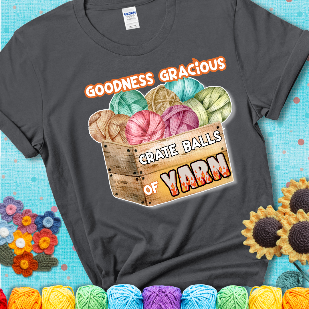 Wooden crate filled with colorful yarn balls and bold text “Goodness Gracious, Crate Balls of Yarn” with flame effects, a funny gift for crocheters showing a charcoal grey tee with a teal sunflower background