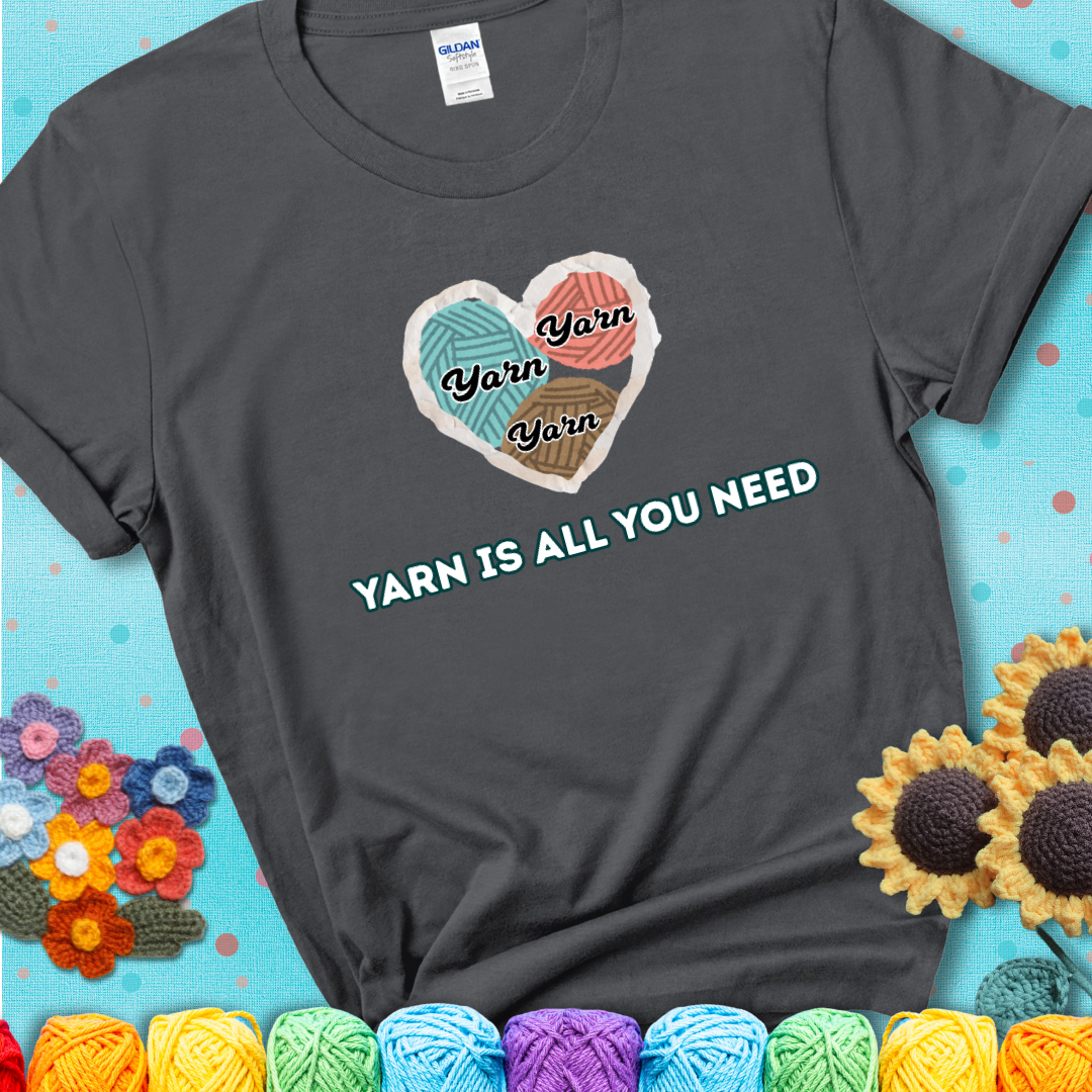 Charcoal t-shirt with a colorful heart made of yarn textures and the phrase “Yarn Is All You Need” in retro lettering.