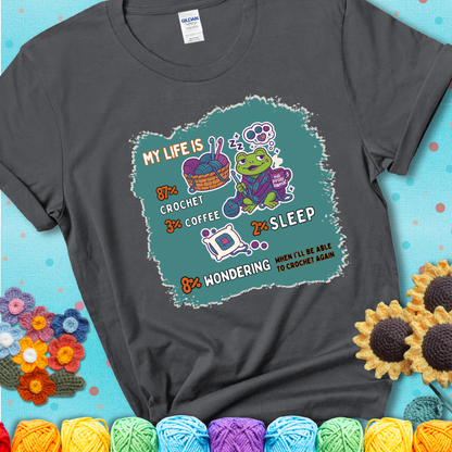 Charcoal t-shirt with a crocheting frog, coffee, yarn, and text showing a playful life breakdown: 87% crochet, 3% coffee, 2% sleep, 8% wondering when to crochet again.