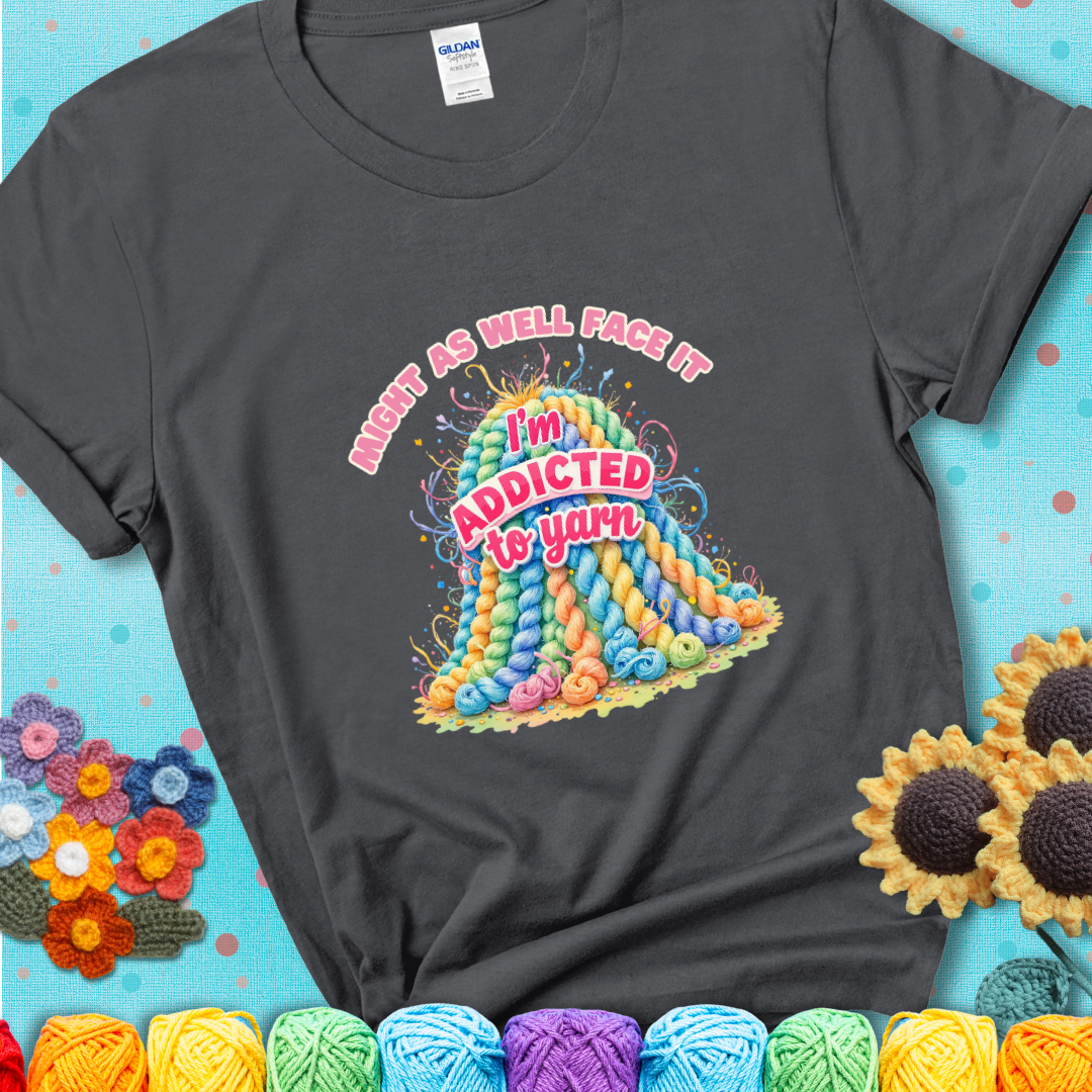 Charcoal t-shirt with a colorful mountain of pastel yarn hanks and the phrase “Might As Well Face It, I’m Addicted To Yarn” in pink and red lettering.