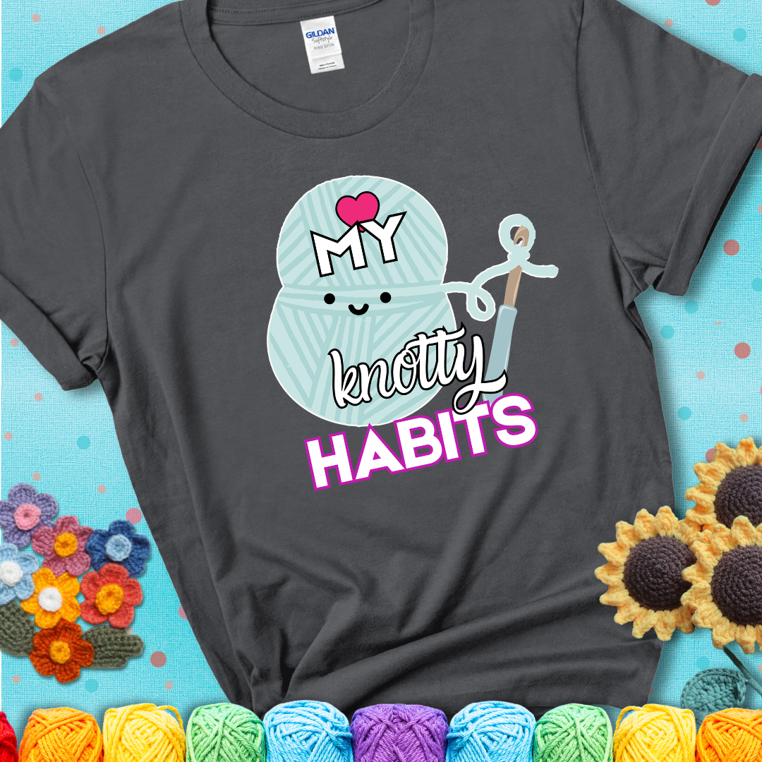 Smiling yarn ball and hook with text “Love My Knotty Habits” - cute crochet shirt with playful design for makers, showing a charcoal grey tee with a teal sunflower background
