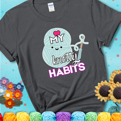 Smiling yarn ball and hook with text “Love My Knotty Habits” - cute crochet shirt with playful design for makers, showing a charcoal grey tee with a teal sunflower background