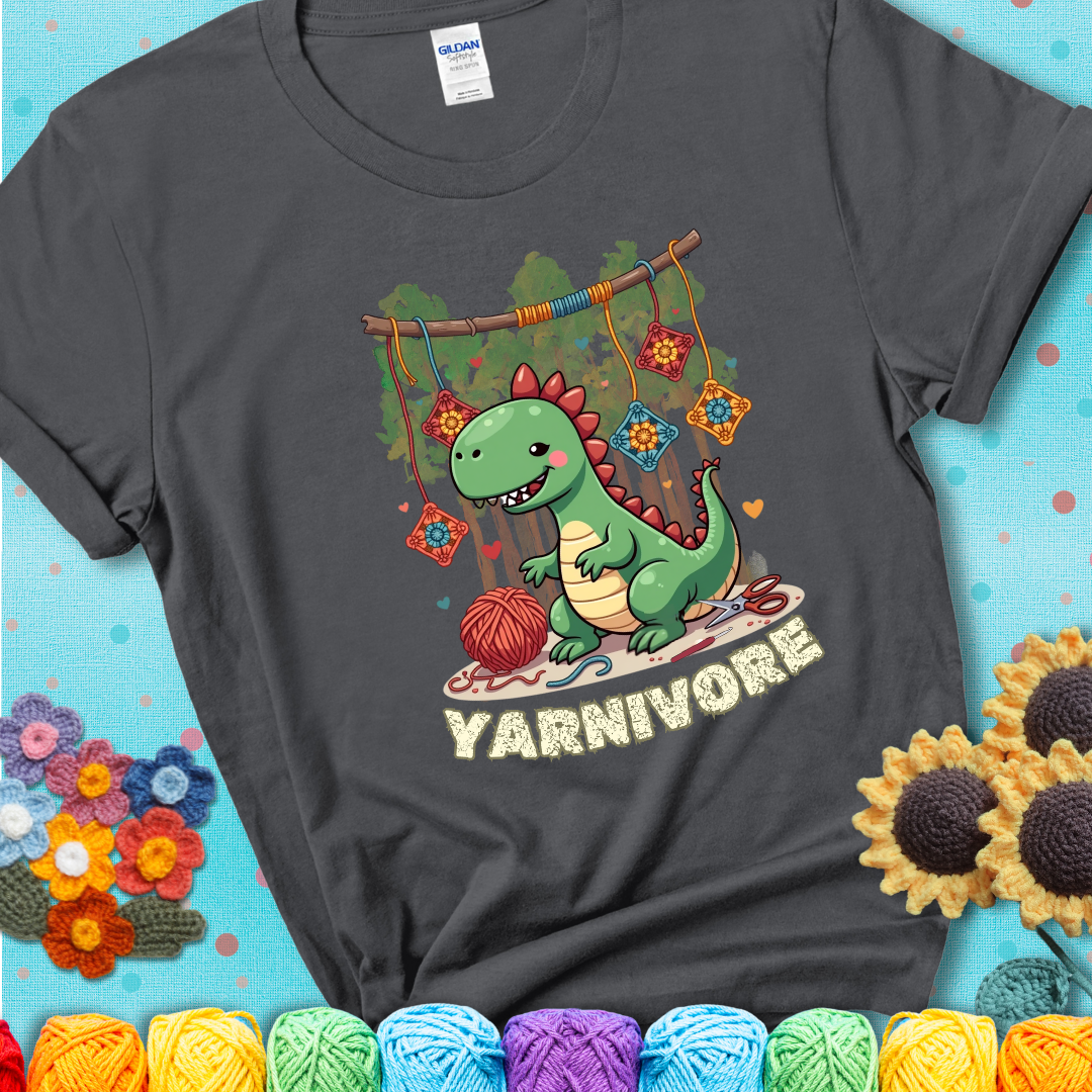 Charcoal grey t-shirt shows a cute green dinosaur with yarn ball and granny squares, text “Yarnivore”, a fun crochet shirt for dino and yarn fans.