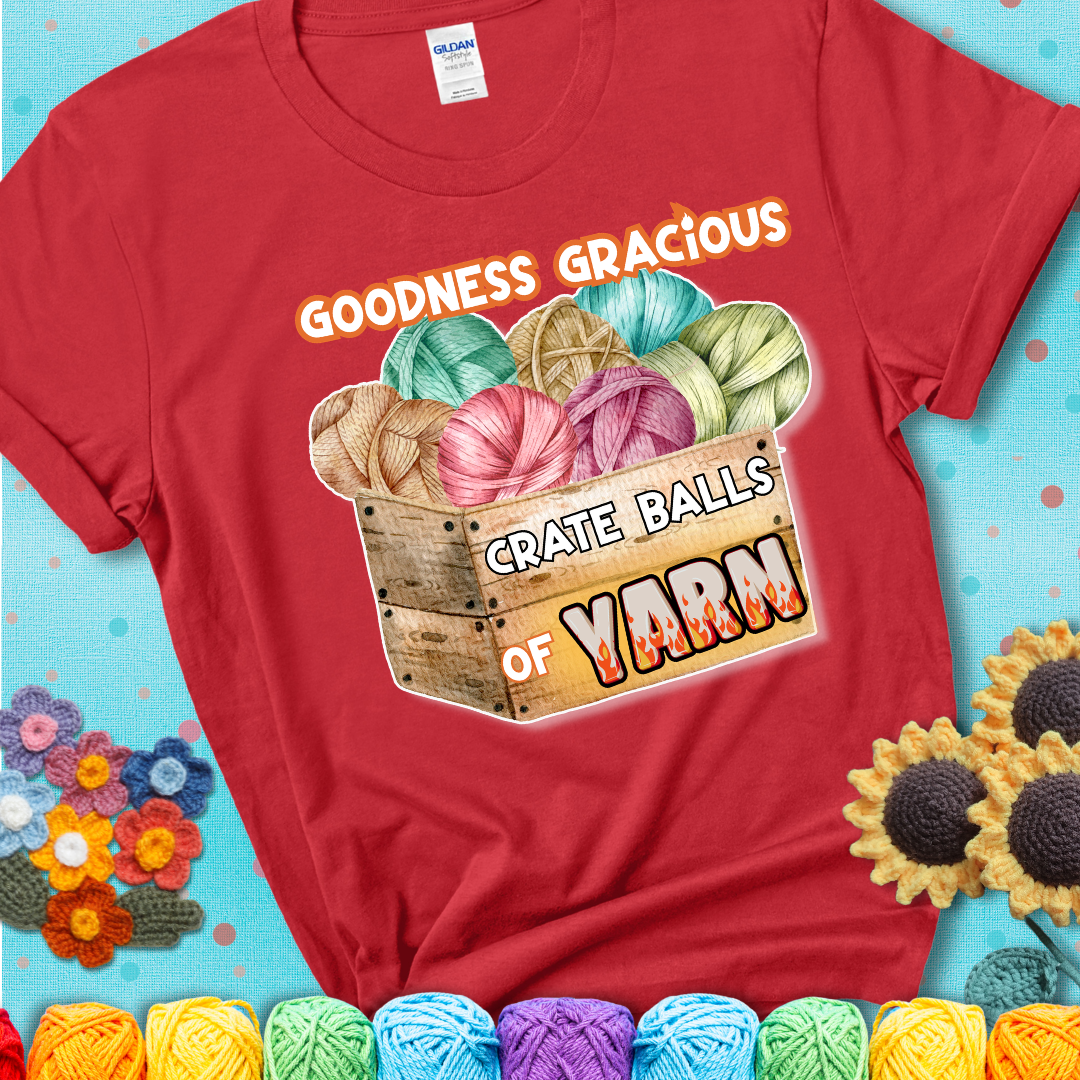 Wooden crate filled with colorful yarn balls and bold text “Goodness Gracious, Crate Balls of Yarn” with flame effects, a funny gift for crocheters showing a red tee with a teal sunflower background