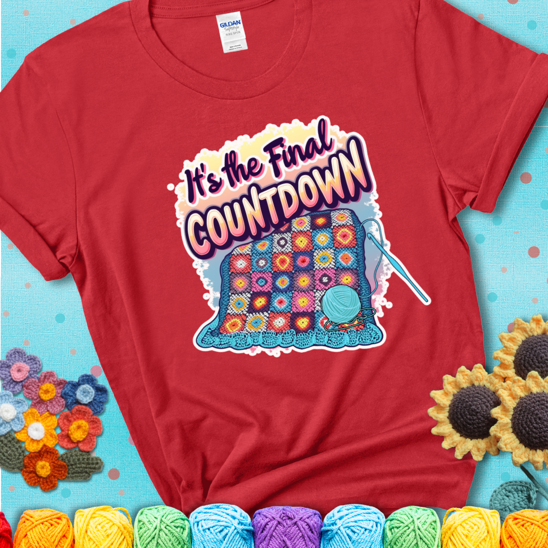 Red t-shirt with a colorful crochet blanket in progress, blue yarn ball, crochet hook, and the phrase “It’s The Final Countdown.”