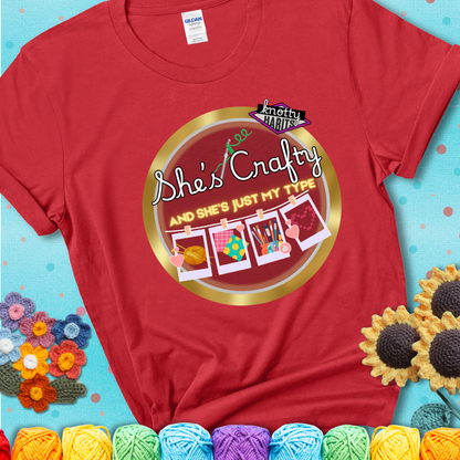 Text on red tee reads "She’s Crafty & She’s Just My Type" with yarn, fabric, painting, and cross-stitch icons hanging like Polaroids