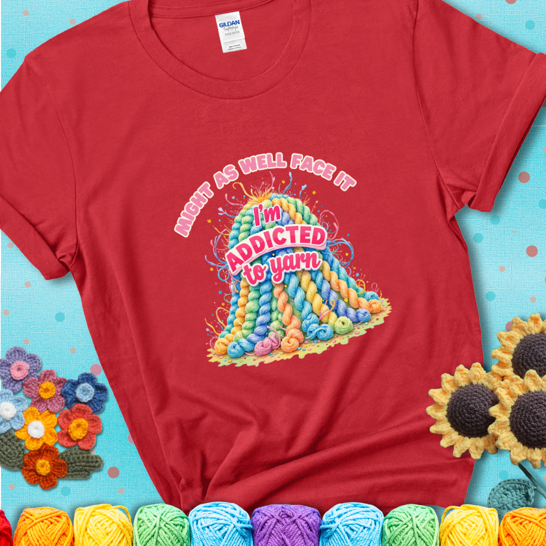 Red t-shirt with a colorful mountain of pastel yarn hanks and the phrase “Might As Well Face It, I’m Addicted To Yarn” in pink and red lettering.