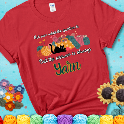 Red t-shirt with a black cat beside a basket of colorful yarn and the phrase, “Not Sure What The Question Was, But The Answer Is Yarn.”