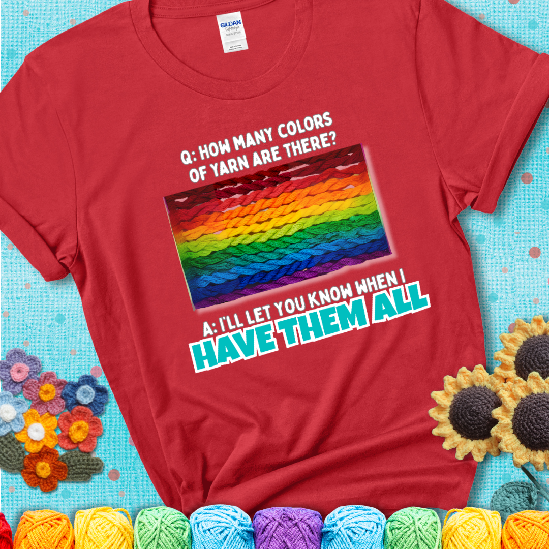 Red t-shirt with rainbow skeins of yarn stacked in color gradient with playful question: “How many colors of yarn are there?” Answer: “I'll let you know when I have them all.”