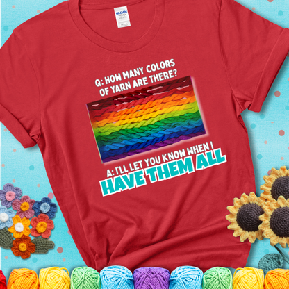 Red t-shirt with rainbow skeins of yarn stacked in color gradient with playful question: “How many colors of yarn are there?” Answer: “I'll let you know when I have them all.”