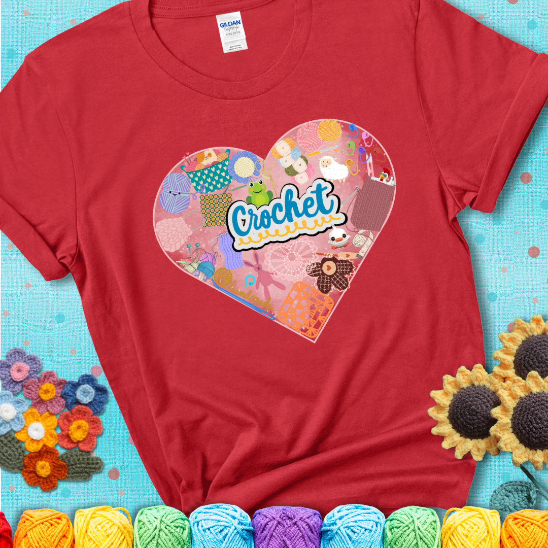A heart filled with colorful crochet essentials including yarn, hooks, scissors, notions, and handmade items, with the word "Crochet" prominently in the center of a red t-shirt.