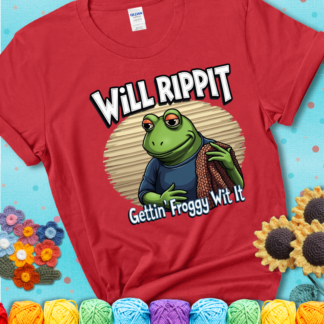 Cool frog holding a yarn blanket. Text reads: “Will Rippit Gettin’ Froggy Wit It.” A hip and humorous crochet red tee for yarn lovers with rhythm.