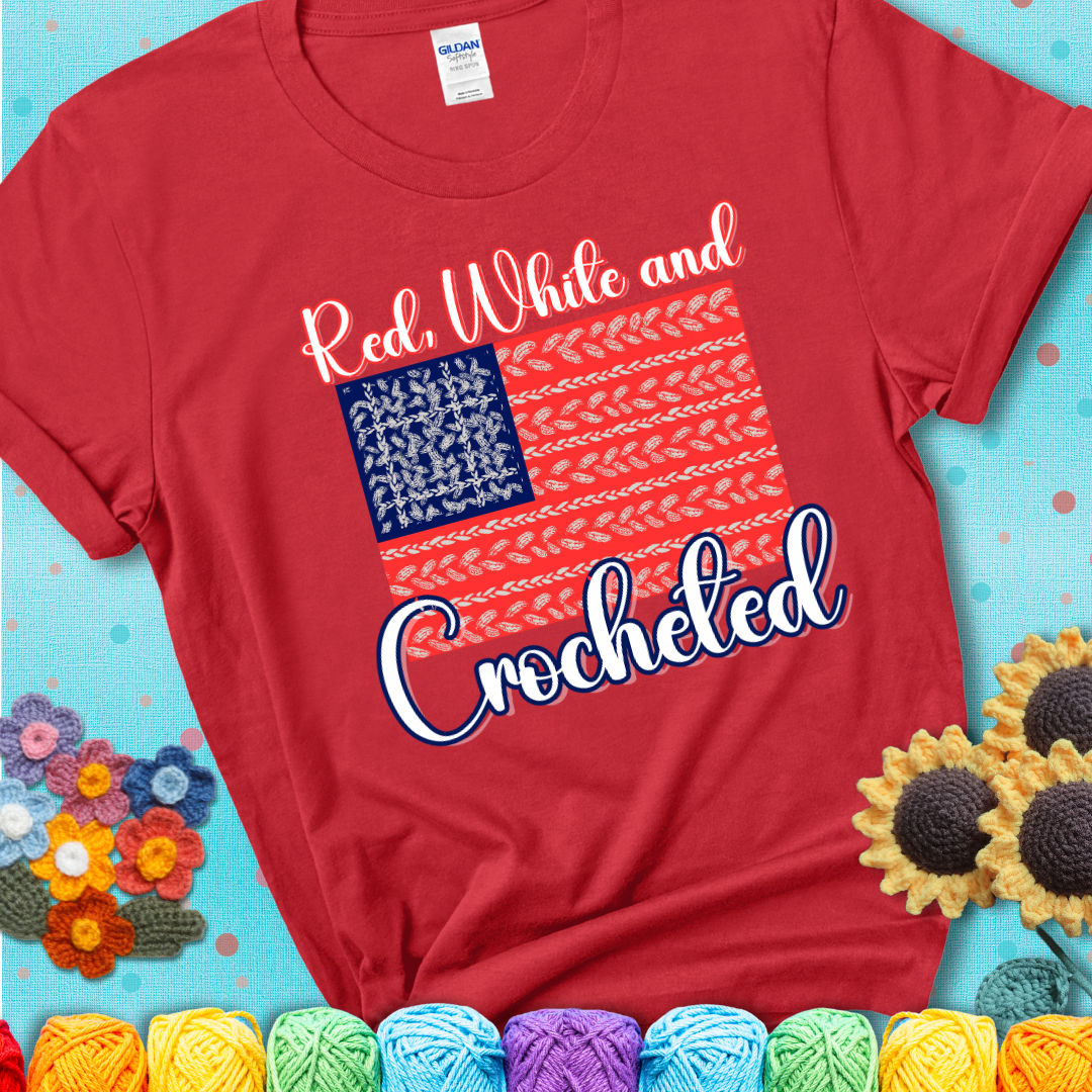 Red t-shirt showing a patriotic crochet-themed American flag design with red and white yarn stitches forming the stripes and blue and white stitches as stars.