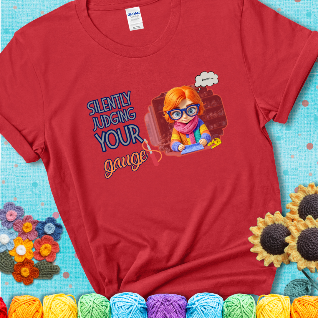 Red t-shirt with a serious-looking crocheter in rainbow clothing and big glasses, holding a tape measure under the phrase “Silently Judging Your Gauge.”