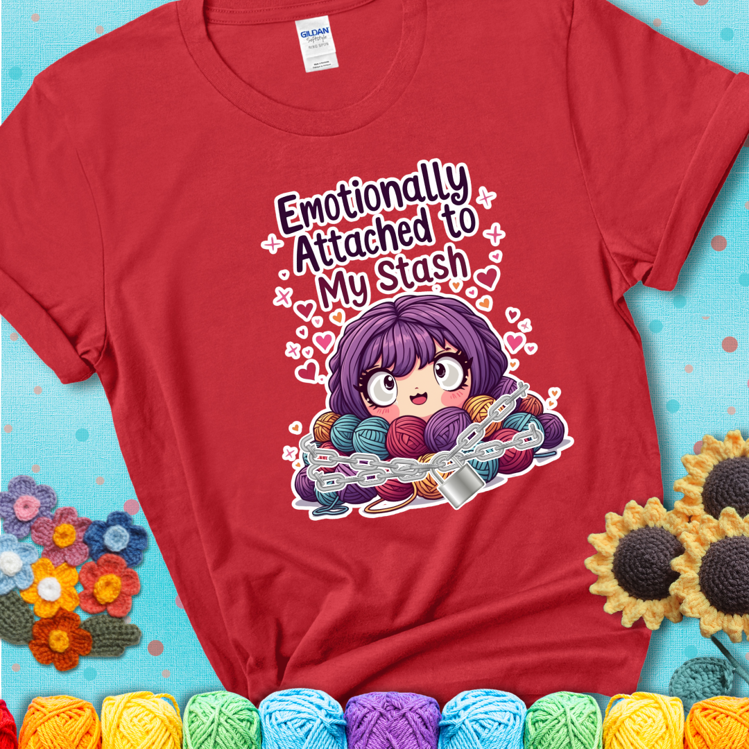 Adorable character with wide eyes hugging a yarn stash wrapped in chains and a lock, with the text “Emotionally Attached to My Stash”  on a red tee.