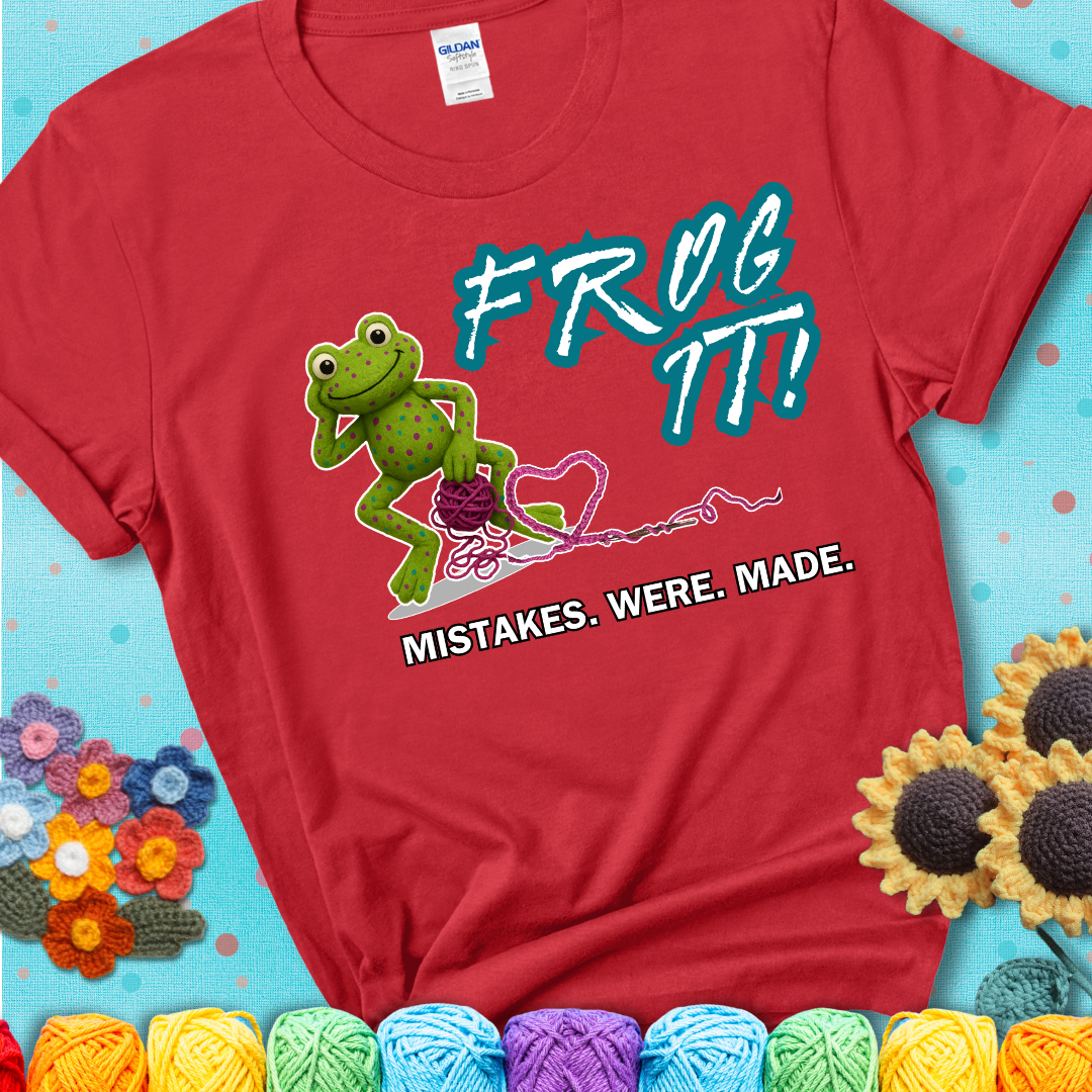 Green frog with yarn and heart-shaped loop. Text reads: “Frog It! Mistakes Were Made.” A playful crochet tee for anyone who's ever had to rip it back, showing a red tee with a teal sunflower background