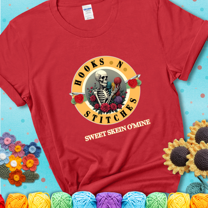 Red t-shirt with a skeleton holding colorful yarn, roses, crochet hooks, and the phrases “Hooks ’N Stitches” and “Sweet Skein O’Mine.”