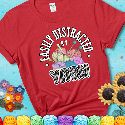If yarn steals your focus every Design reads 'Easily Distracted By Yarn', perfect crochet gift for yarn lovers; showing a red tee with a teal sunflower background