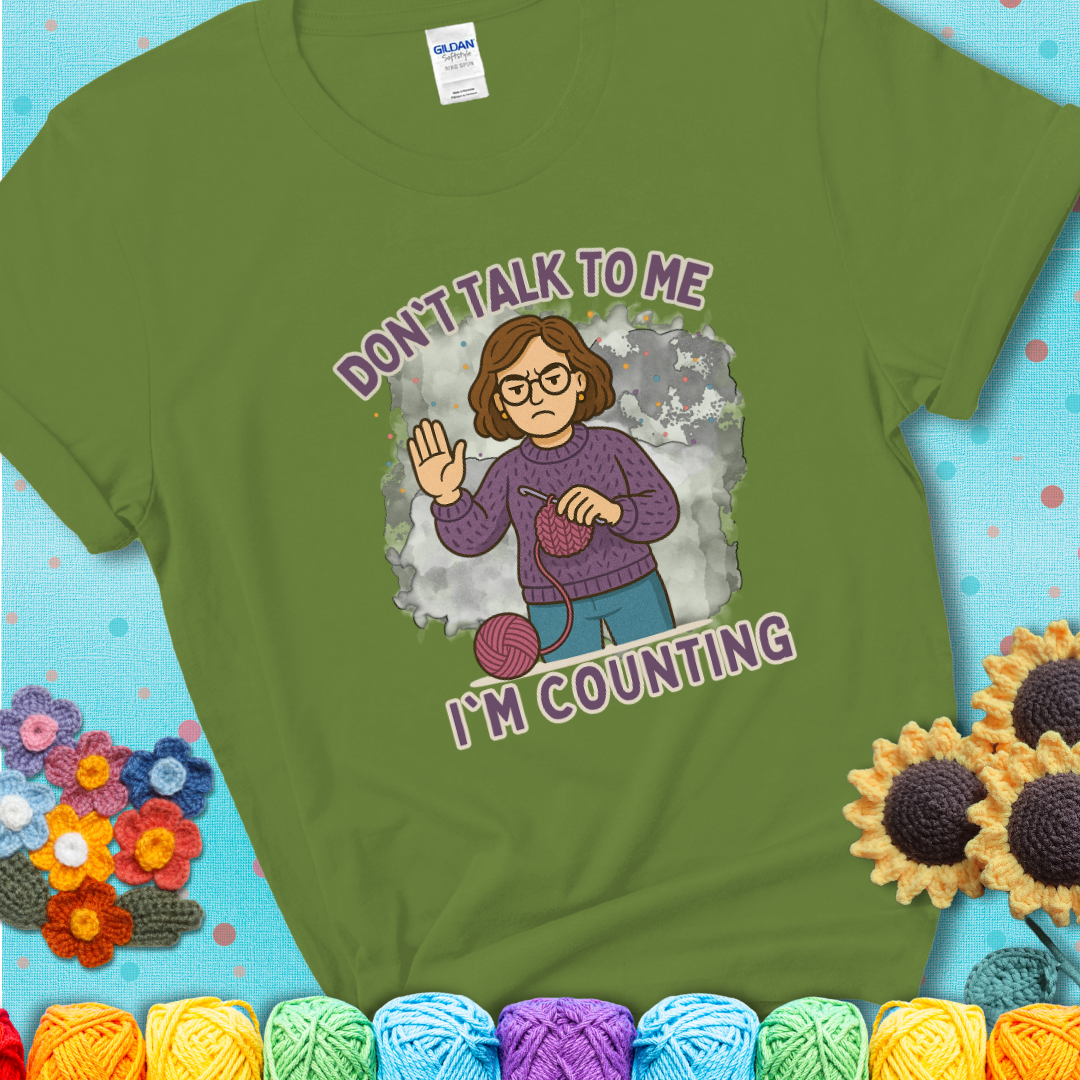 Kiwi t-shirt with an annoyed maker holding up a hand beside yarn, with the phrase “Don’t Talk To Me, I’m Counting.”
