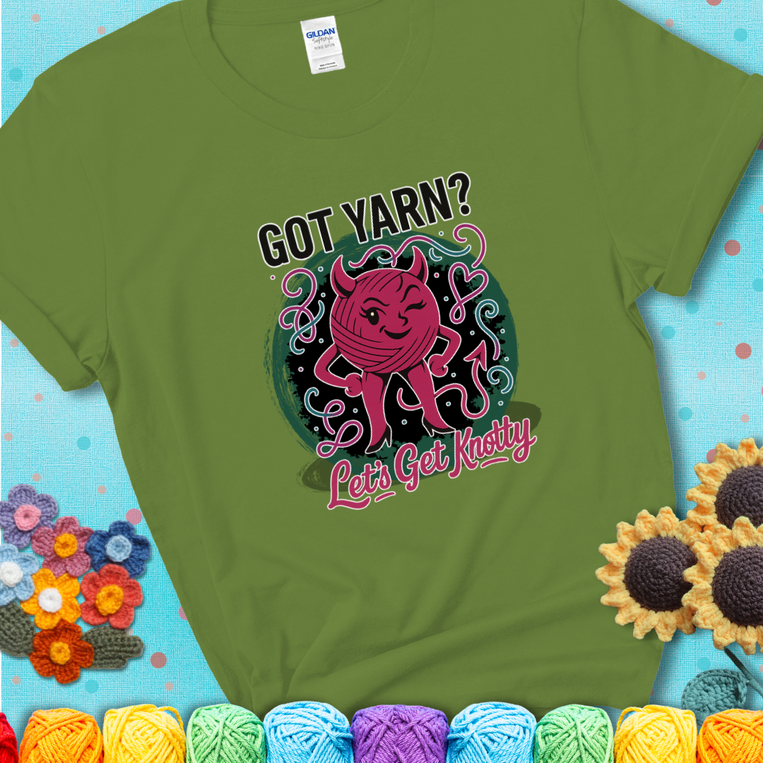 Kiwi green t-shirt with a cheeky pink yarn ball wearing devil horns, arms, and legs, winking beneath the phrase “Got Yarn? Let’s Get Knotty