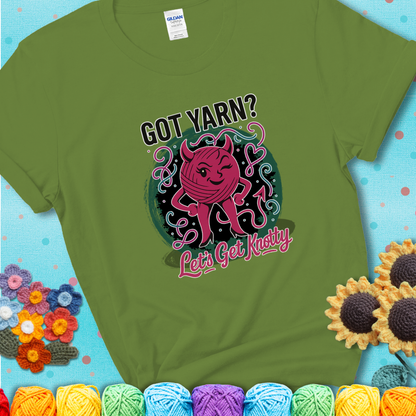 Kiwi green t-shirt with a cheeky pink yarn ball wearing devil horns, arms, and legs, winking beneath the phrase “Got Yarn? Let’s Get Knotty