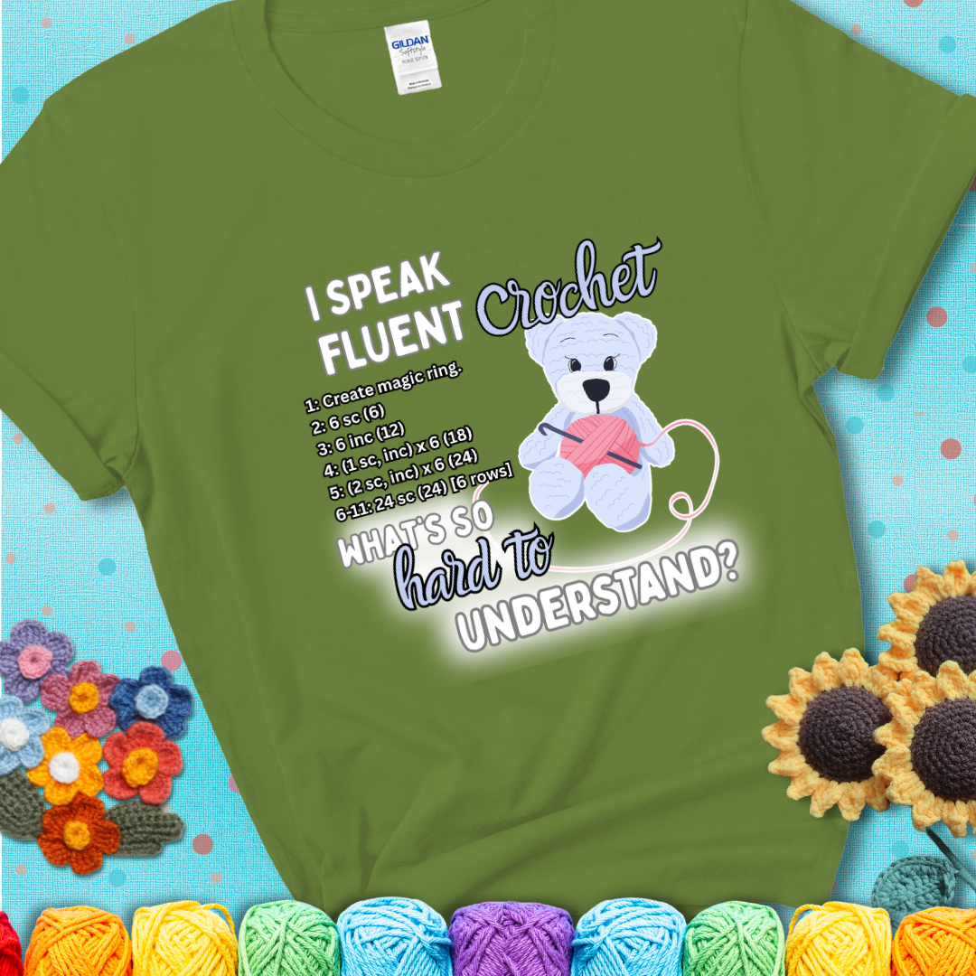 A cute crochet bear holding a yarn ball, surrounded by a short crochet pattern. The phrase reads “I Speak Fluent Crochet – What’s so hard to understand?” on a green t-shirt.