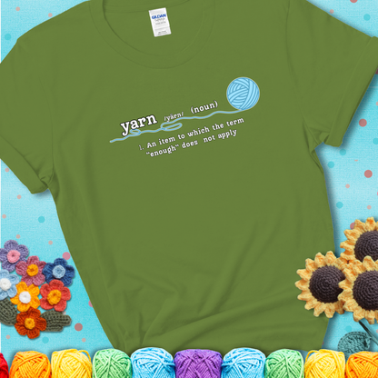 Kiwi t-shirt with a definition-style yarn graphic reading “An item to which the word ‘enough’ does not apply,” plus a blue ball of yarn with a loose strand.