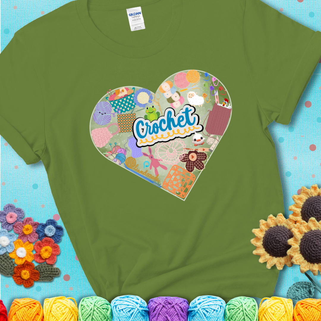 A heart filled with colorful crochet essentials including yarn, hooks, scissors, notions, and handmade items, with the word "Crochet" prominently in the center of a green t-shirt.
