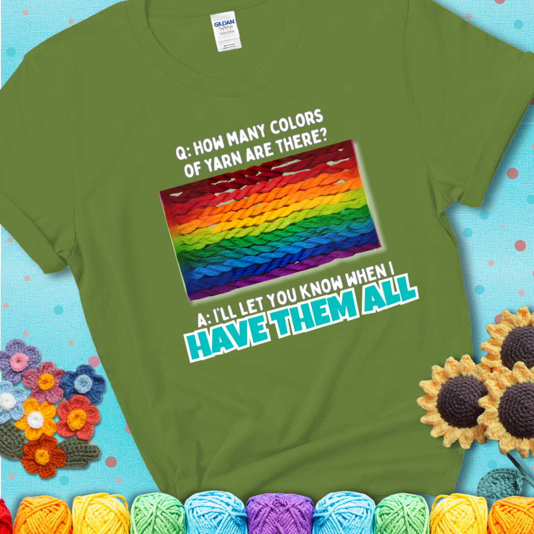 Green t-shirt with rainbow skeins of yarn stacked in color gradient with playful question: “How many colors of yarn are there?” Answer: “I'll let you know when I have them all.”