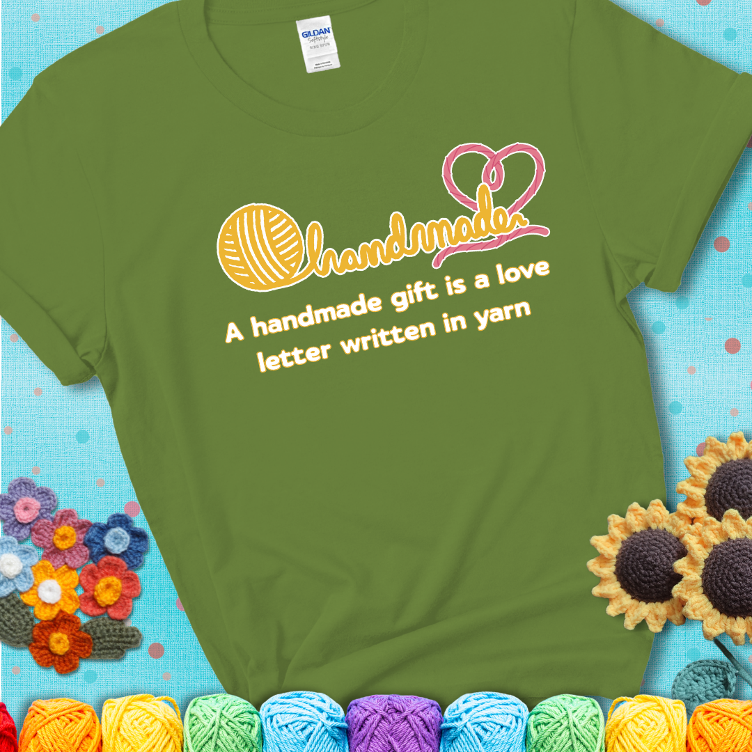 Soft script-style design with heart detail. Text reads: “A Handmade Gift Is a Love Letter Written in Yarn.” A sweet and sentimental shirt for crocheters who craft from the heart, showing a green tee with a teal sunflower background