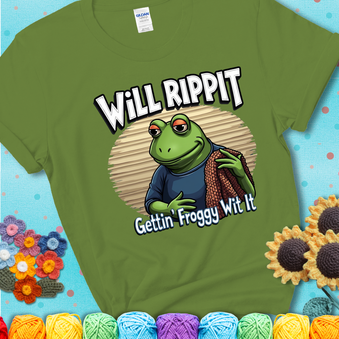 Cool frog holding a yarn blanket. Text reads: “Will Rippit Gettin’ Froggy Wit It.” A hip and humorous crochet green tee for yarn lovers with rhythm.