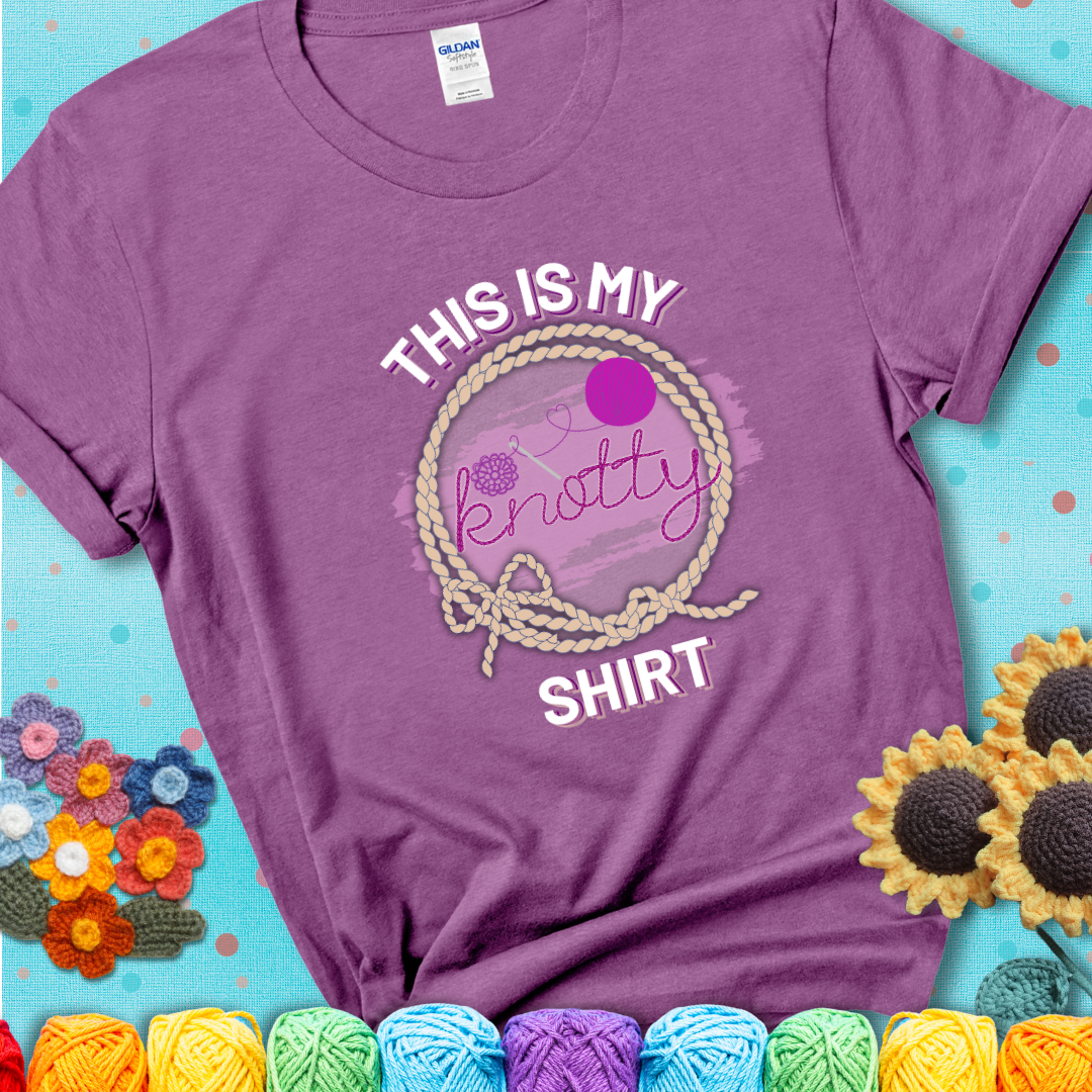 Heather Radiant Orchid t-shirt with the phrase “This is My Knotty Shirt” inside a rope circle, featuring a yarn ball and crochet hook forming the word “knotty.”