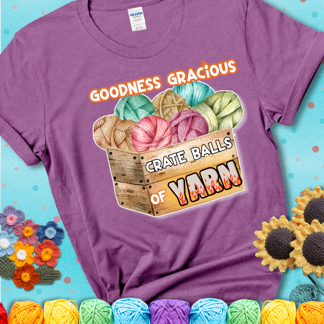 Wooden crate filled with colorful yarn balls and bold text “Goodness Gracious, Crate Balls of Yarn” with flame effects, a funny gift for crocheters showing a lavender tee with a teal sunflower background