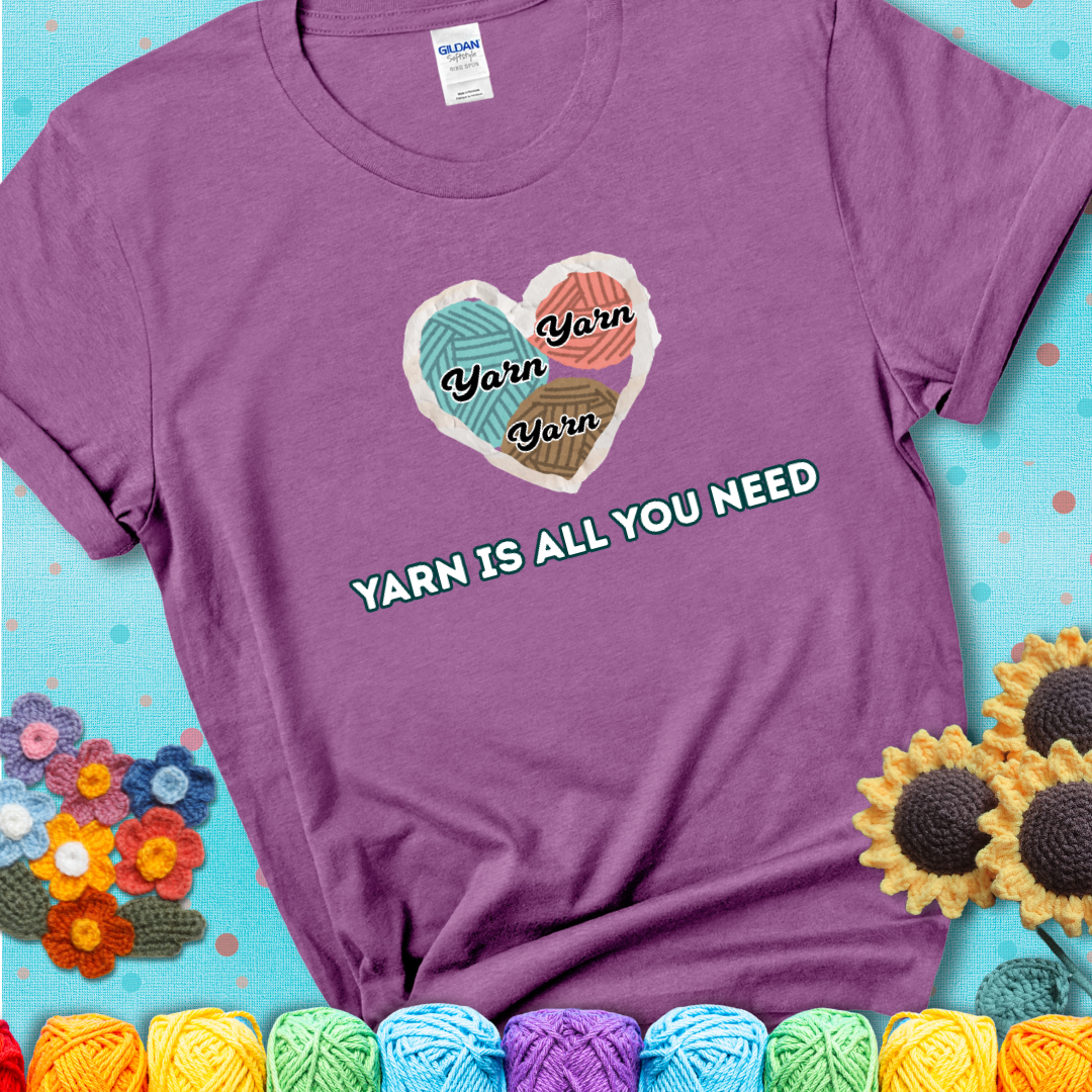 Heather Radiant Orchid t-shirt with a colorful heart made of yarn textures and the phrase “Yarn Is All You Need” in retro lettering.