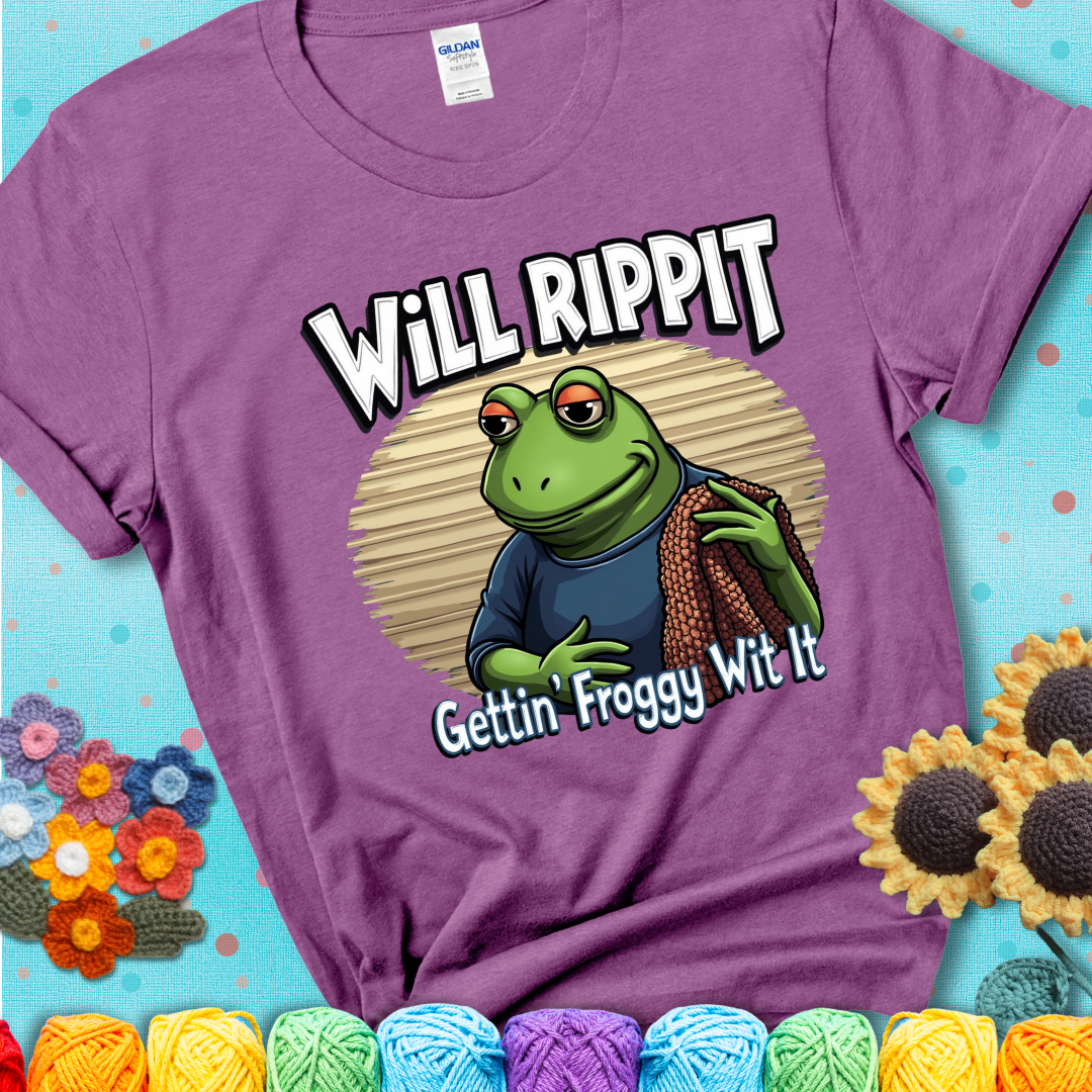Cool frog holding a yarn blanket. Text reads: “Will Rippit Gettin’ Froggy Wit It.” A hip and humorous crochet lavender tee for yarn lovers with rhythm.
