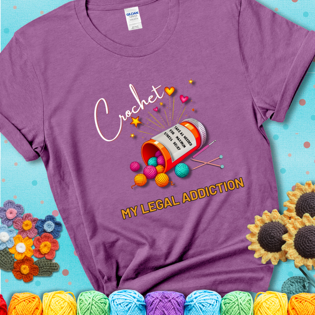 Heather radiant orchid t-shirt with a prescription bottle spilling colorful yarn balls, small crochet details, and the phrase “Crochet: My Legal Addiction.”